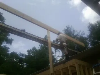 Carpenter setting a ridge beam over a new addition frame — Ice Dam Removal by Roofing Brothers in Brian Head