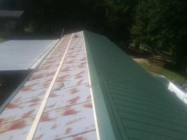 Old rusted panels beside newly installed green metal roofing — Wind Damage Roof Repair by Roofing Brothers in Brian Head