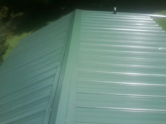 New green metal panels meeting at the ridge of a roof — Flat Roof Repair work by our crew in Brian Head