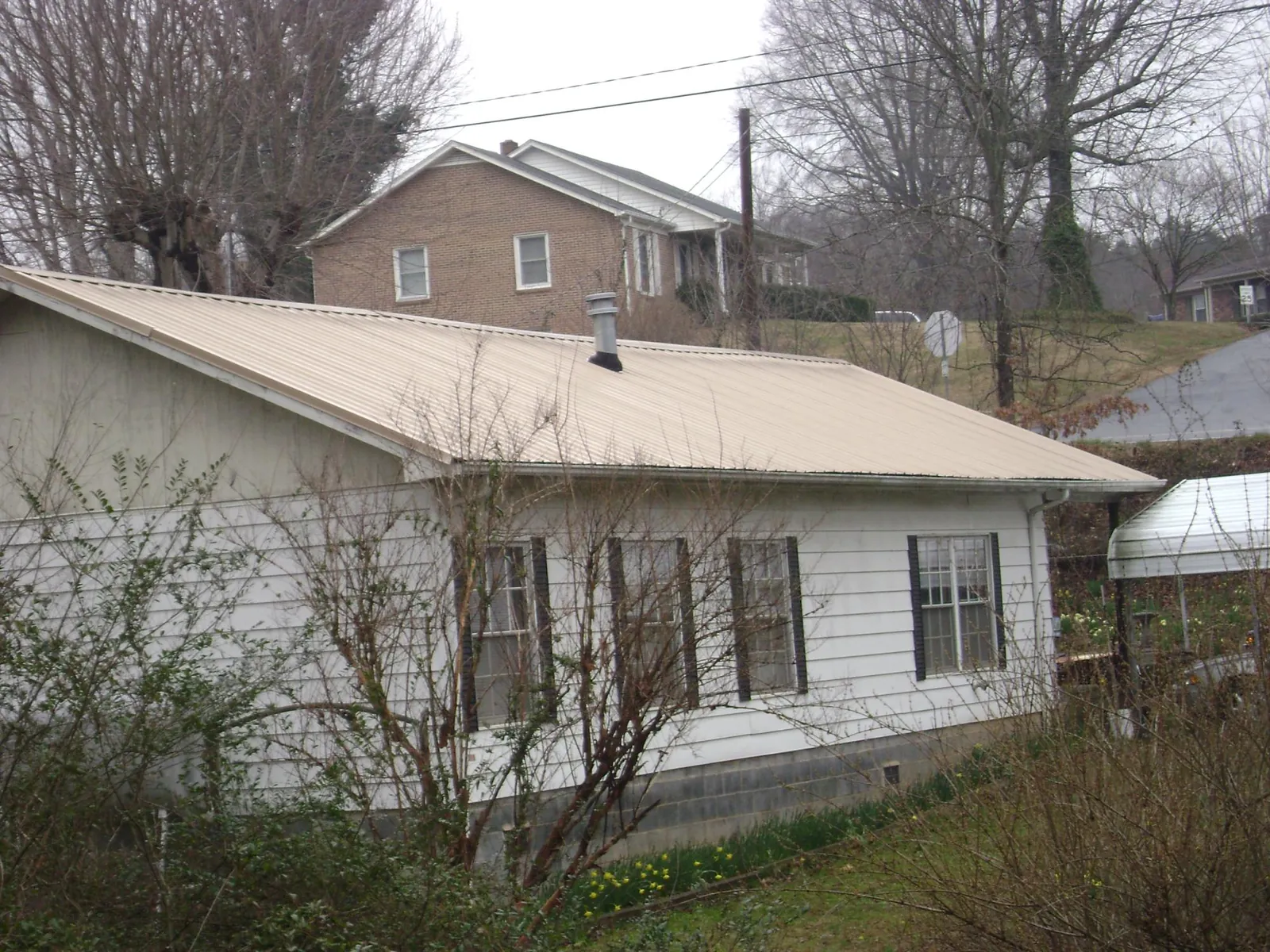 Tan metal roof on a white sided house set into a hillside — Commercial Roofing by Roofing Brothers in Brian Head
