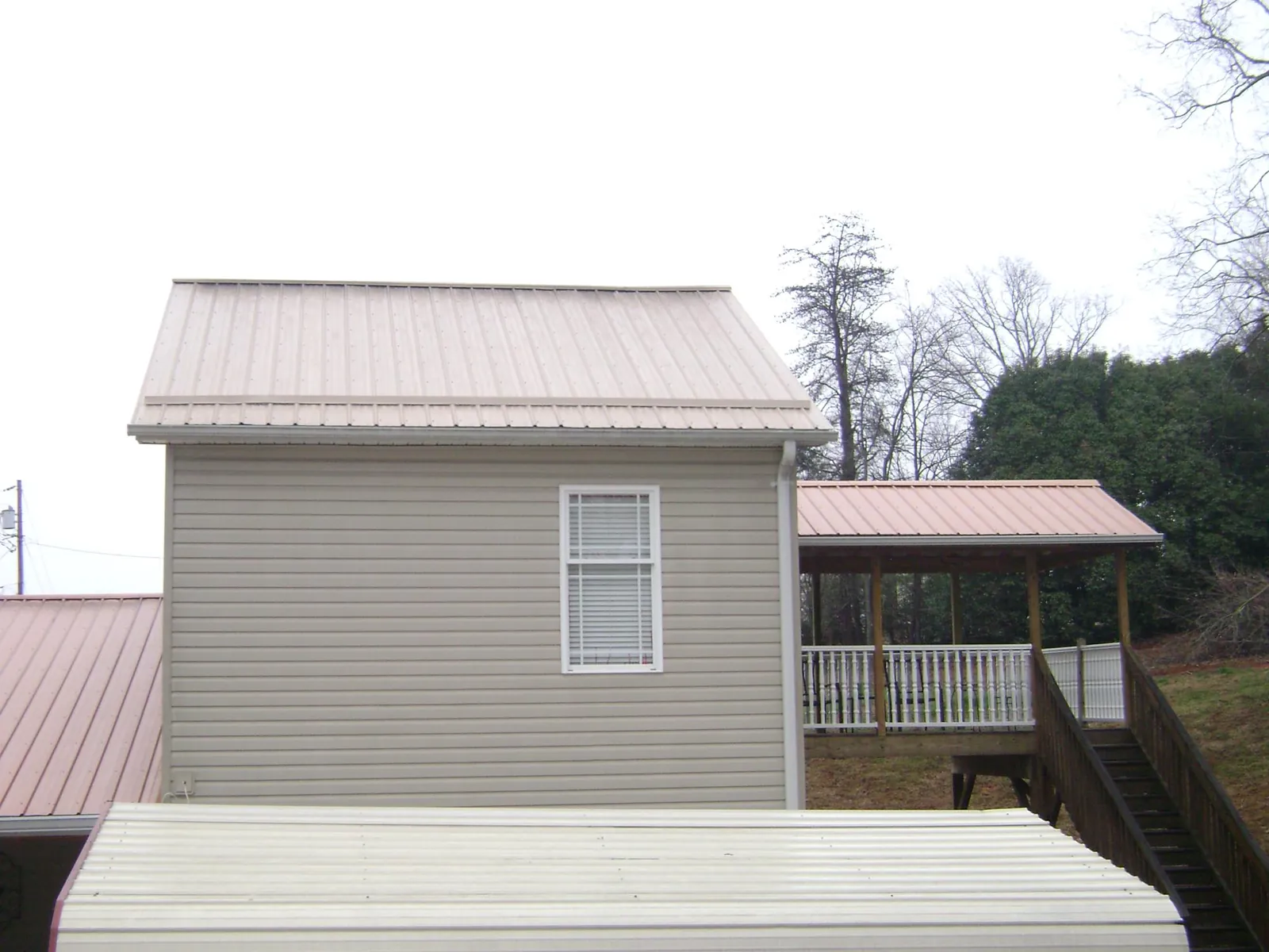 Tan metal roofs on a two story addition and attached porch, from a Roof Replacement job in Brian Head