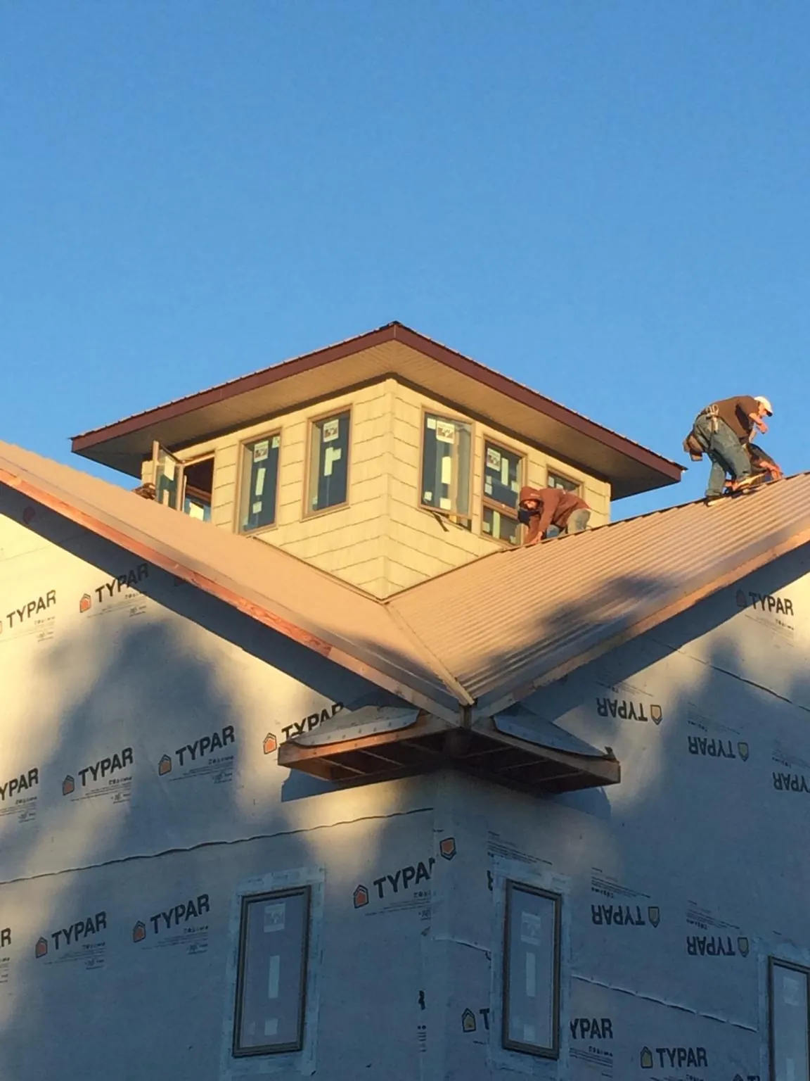 Roofers working around a rooftop cupola on a new metal roof at sunset — Roof Waterproofing in Brian Head by Roofing Brothers